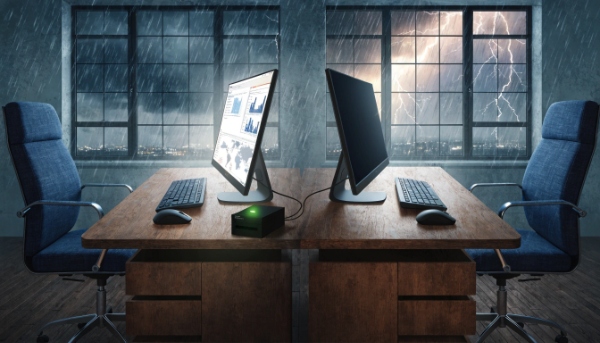 An office during a power outage, with one computer on (with a good UPS) and another computer off (with a dead UPS battery)