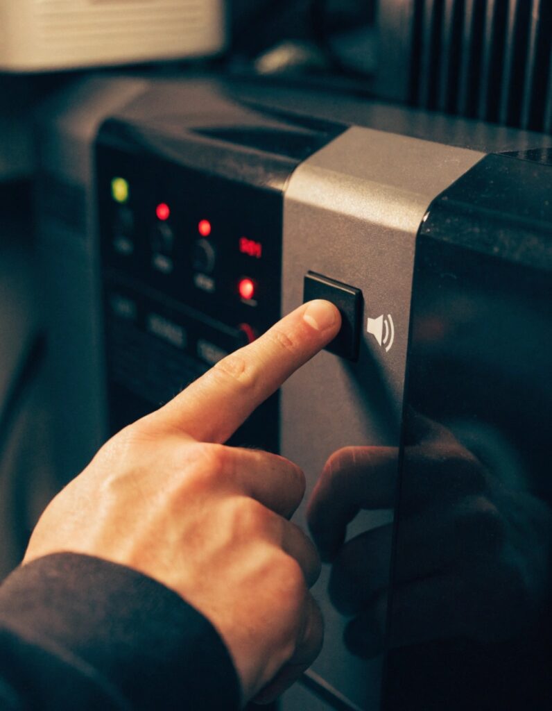 A hand reaching out to press a button on a UPS front panel, with a 'mute' icon next to the button clearly visible