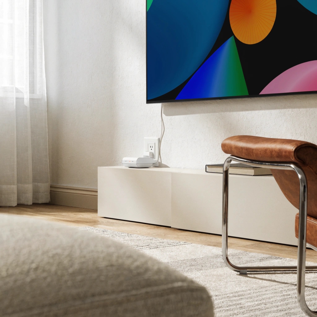 A sleek, modern TV connected to a small, discreet voltage stabilizer, which looks more appropriate in a living room than a bulky UPS.